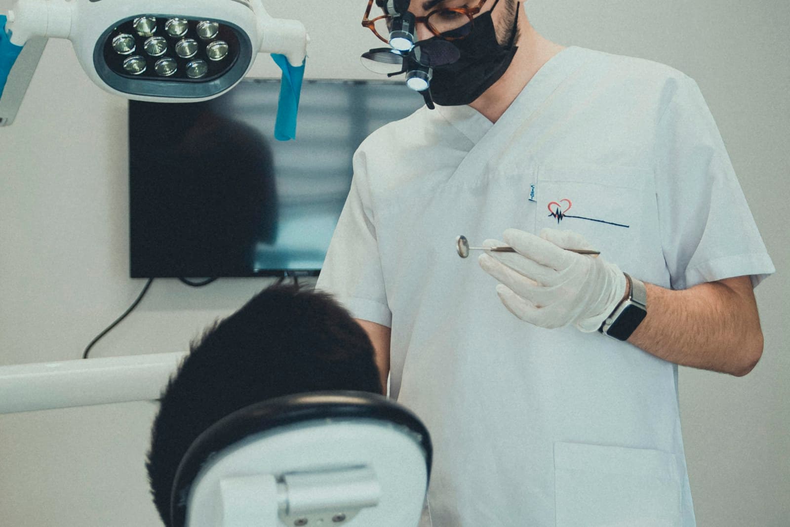 A dentist reviewing a patient beside the chair light during an appointment
