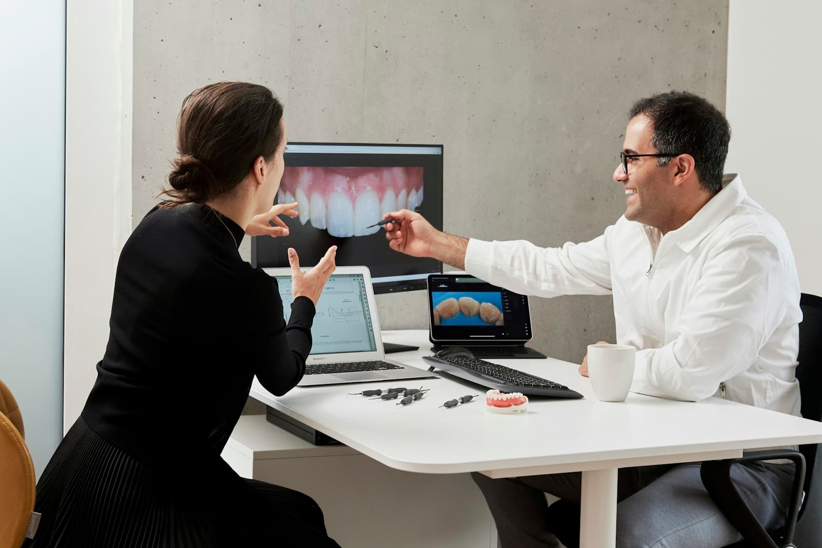 A dentist and patient across a desk looking at a scan together during a consultation