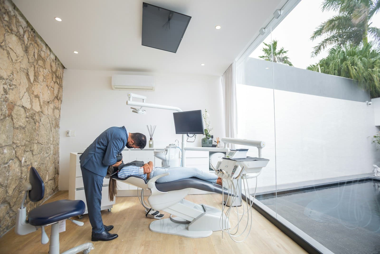 A dentist leaning in to talk with a relaxed patient during a routine check-up